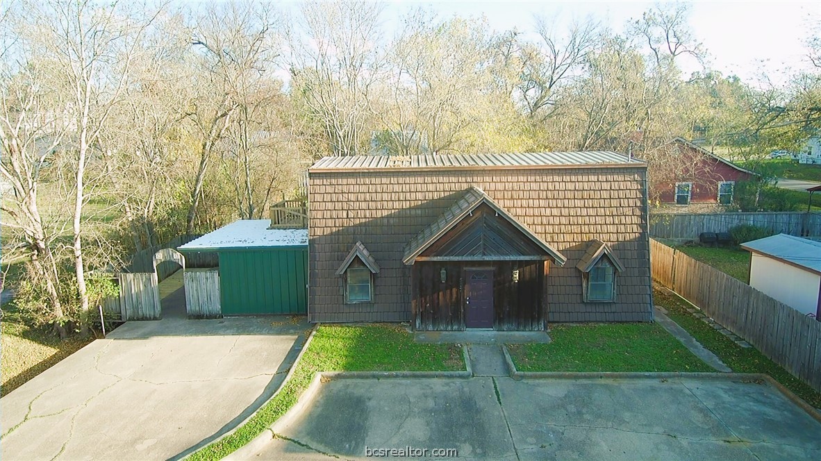 a view of a house with a yard plants and a large tree