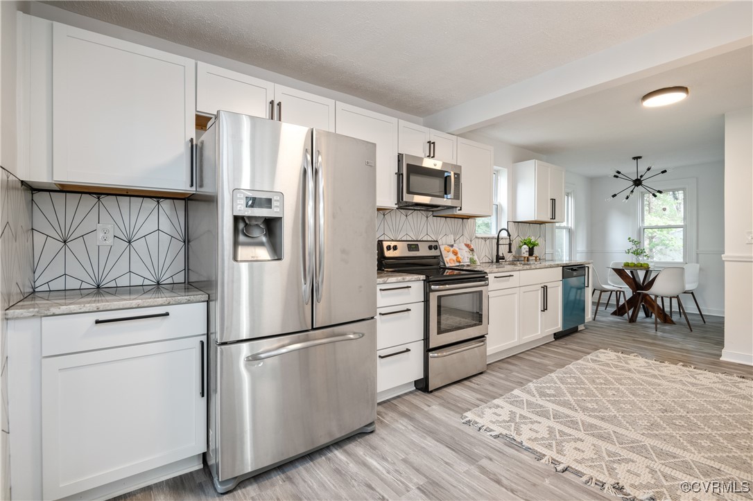 Kitchen with light wood-type flooring, backsplash,