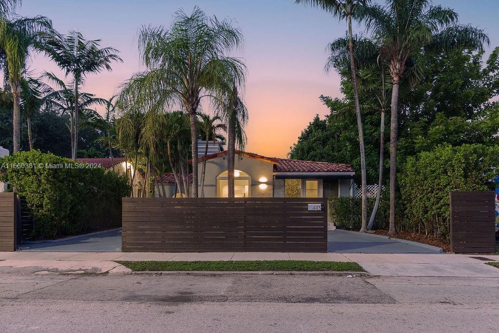 a view of a house with a yard and palm trees