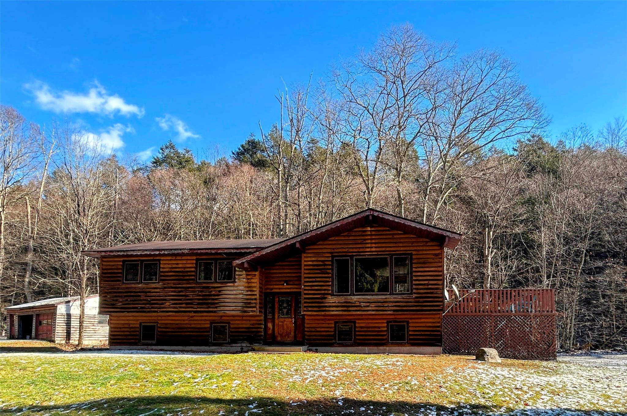 Log home featuring a deck and a front lawn