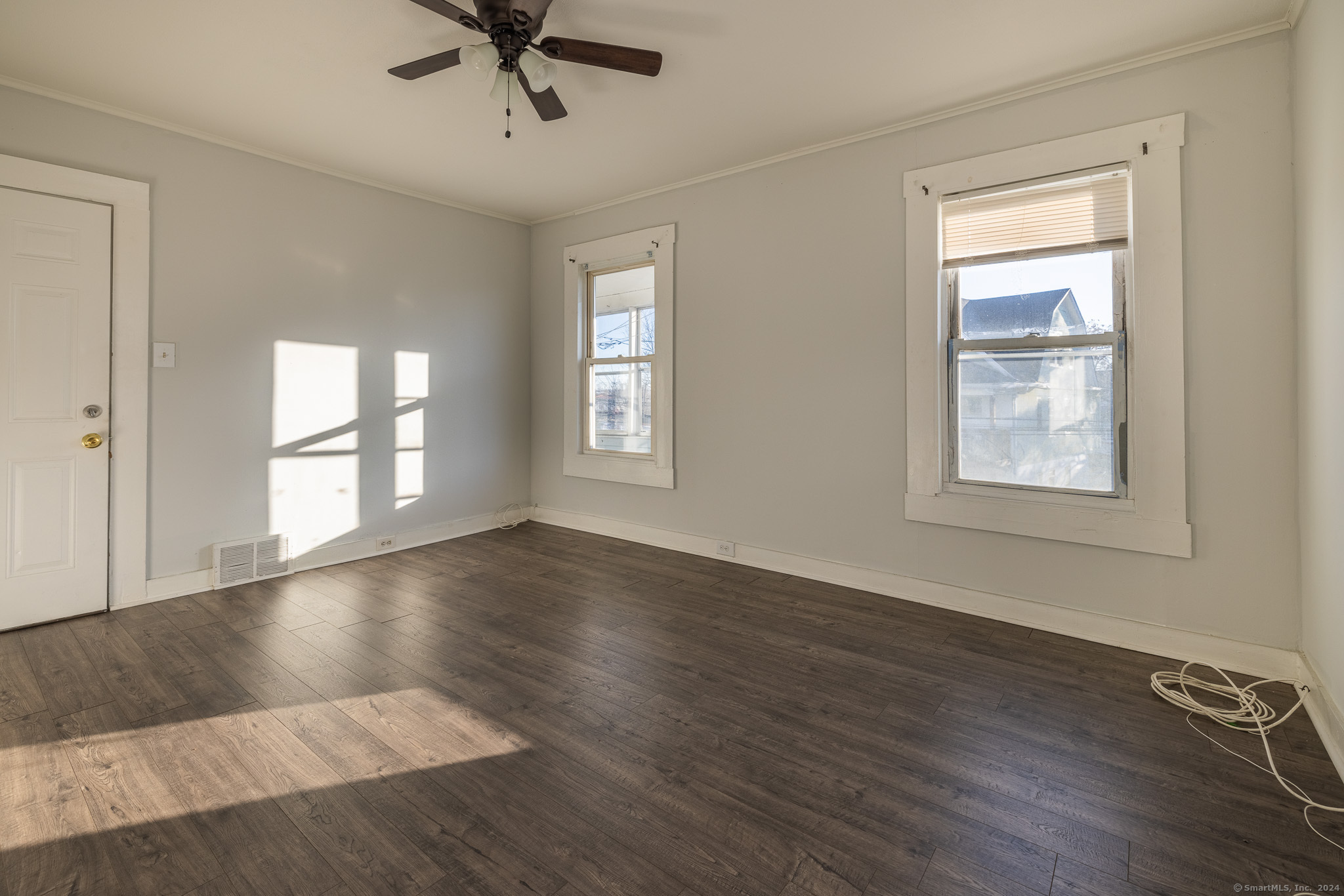 a view of an empty room with a window and wooden floor