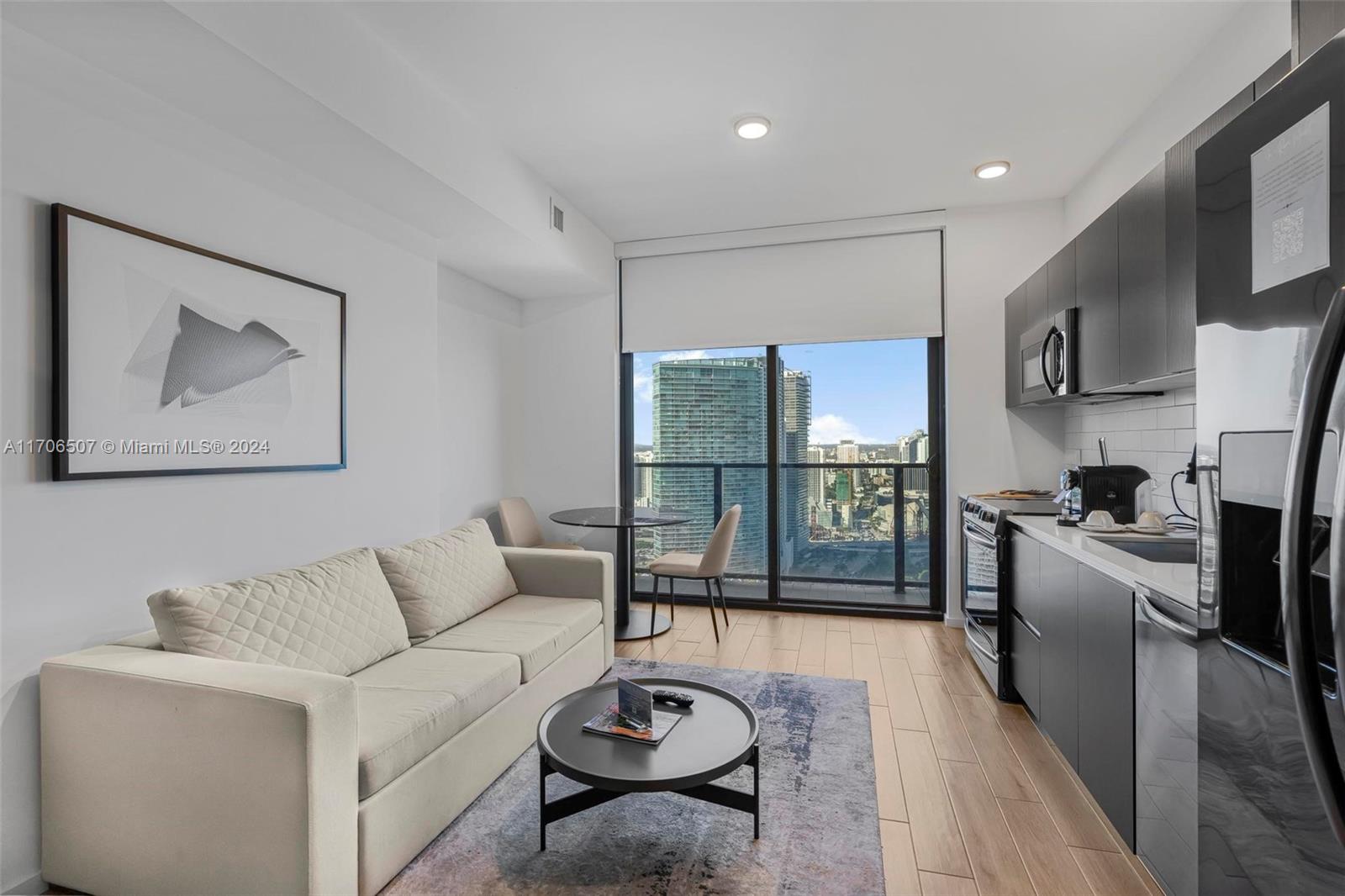 a living room with furniture a refrigerator and kitchen view