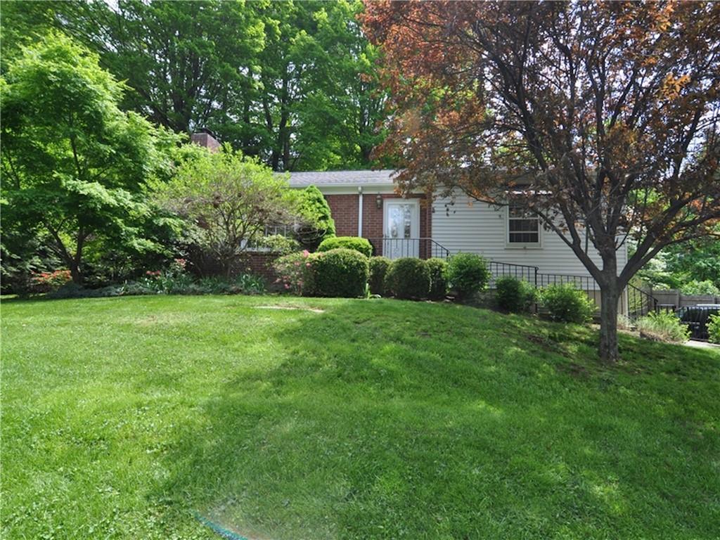 a view of a house with a yard and a large tree