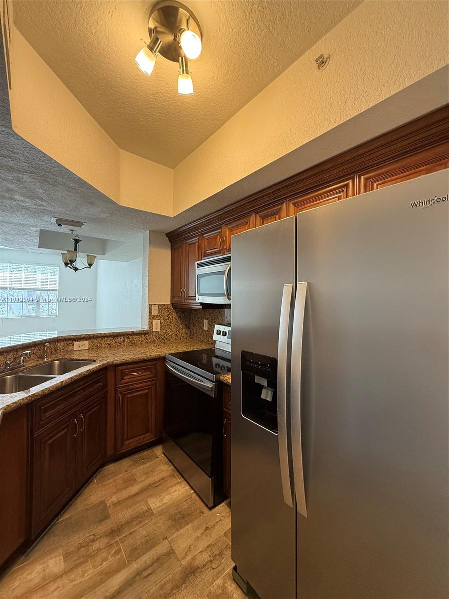 a kitchen with stainless steel appliances granite countertop a refrigerator and a sink