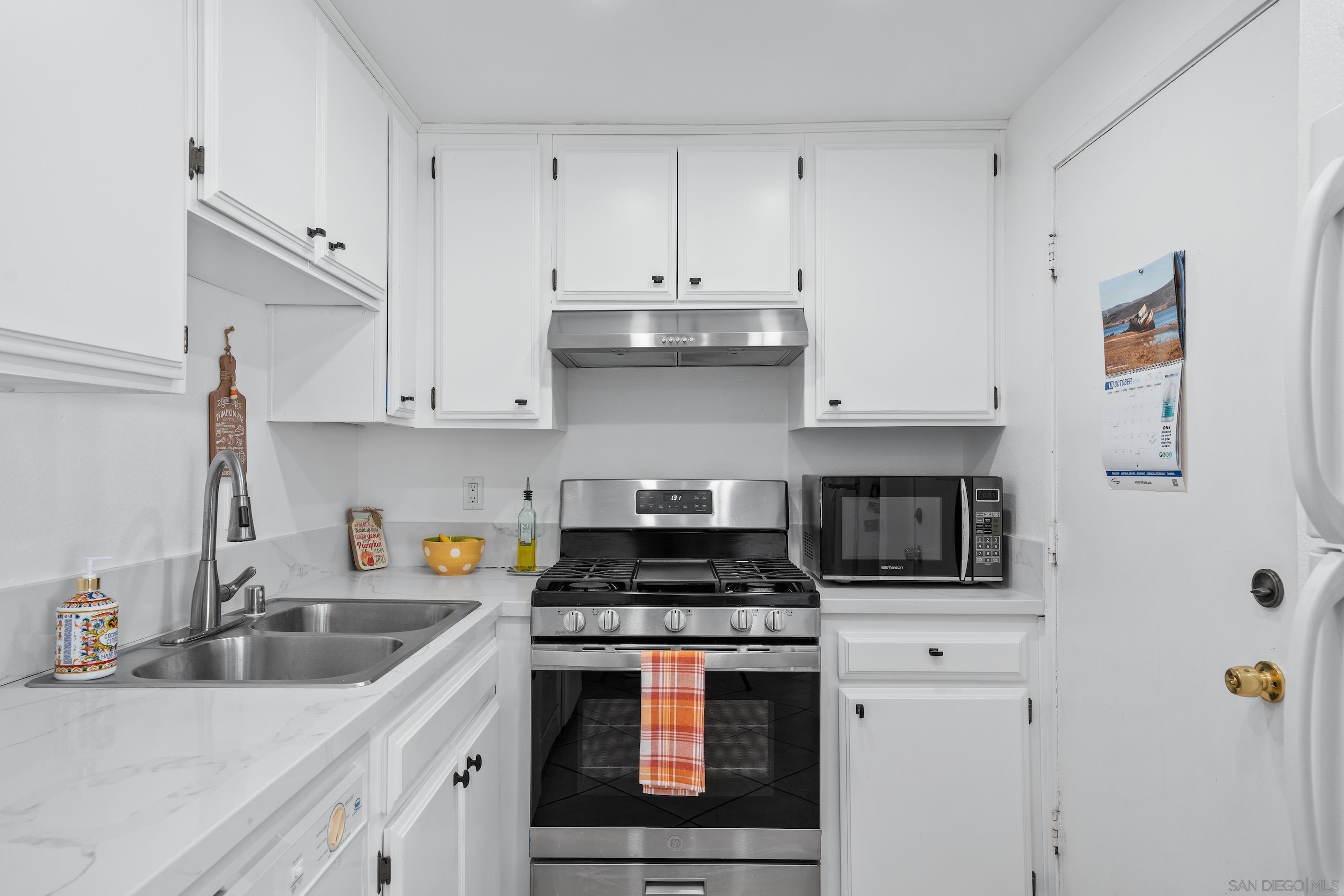 a kitchen with stainless steel appliances a stove and white cabinets