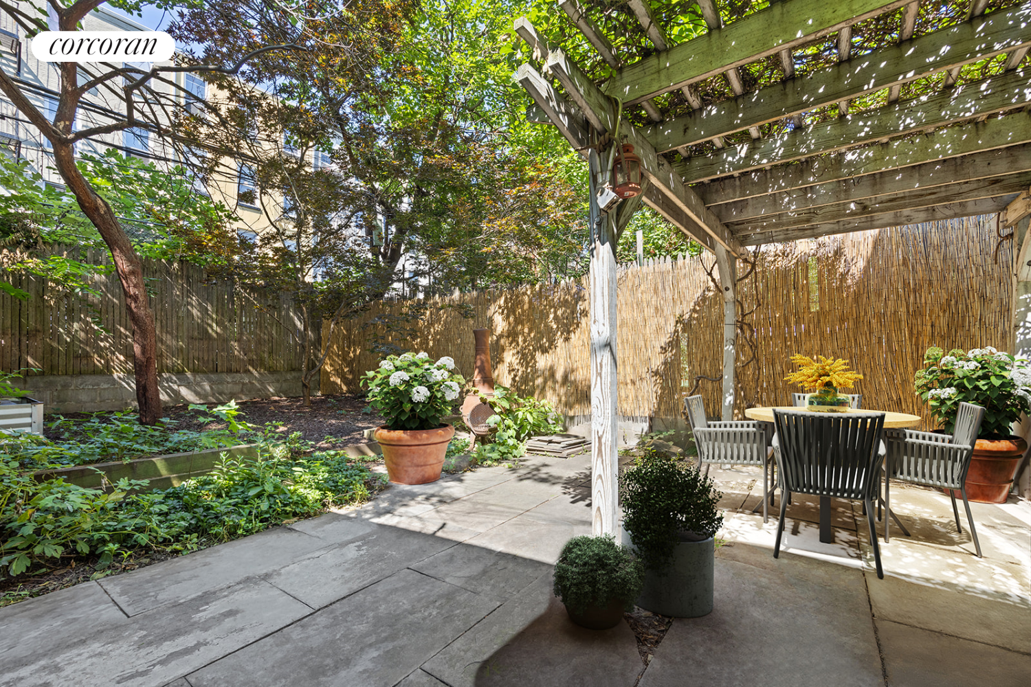 a view of a patio with table and chairs potted plants and large tree