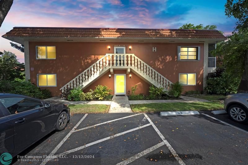 a view of a car park in front of a brick house with a yard