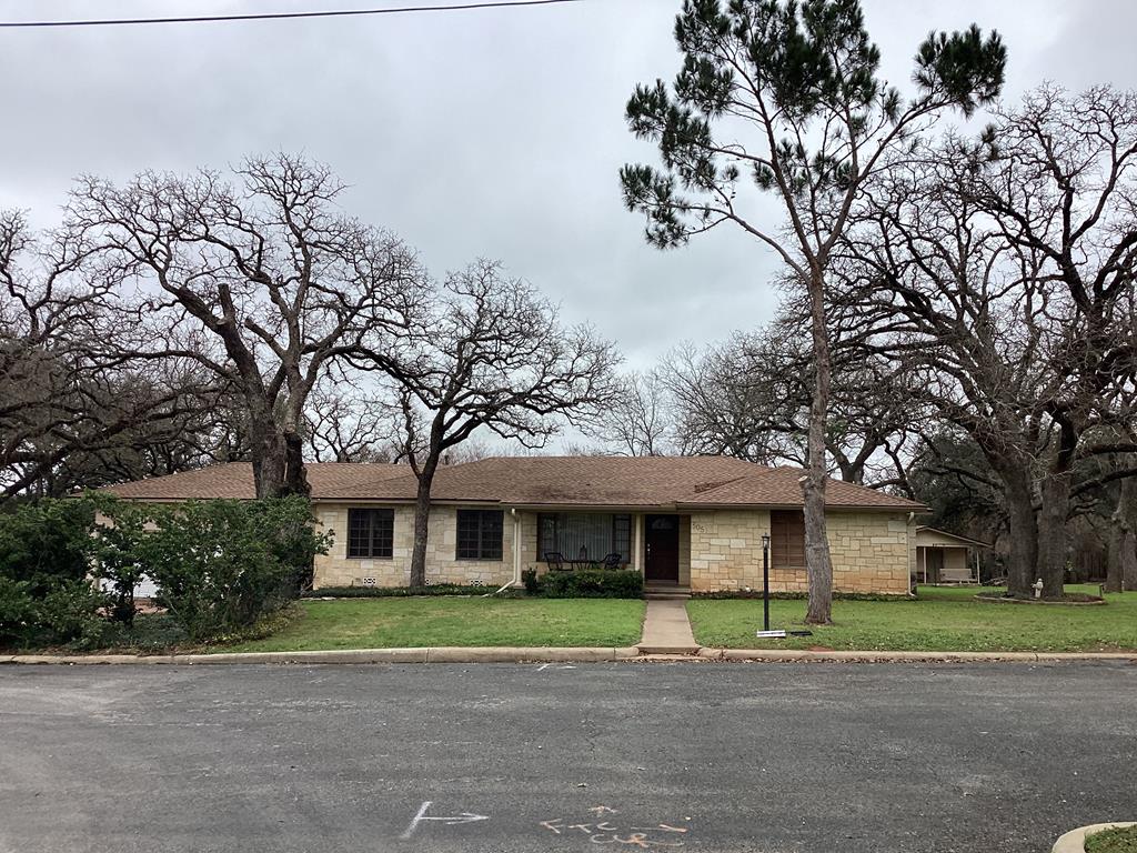 a front view of a house with a garden and trees