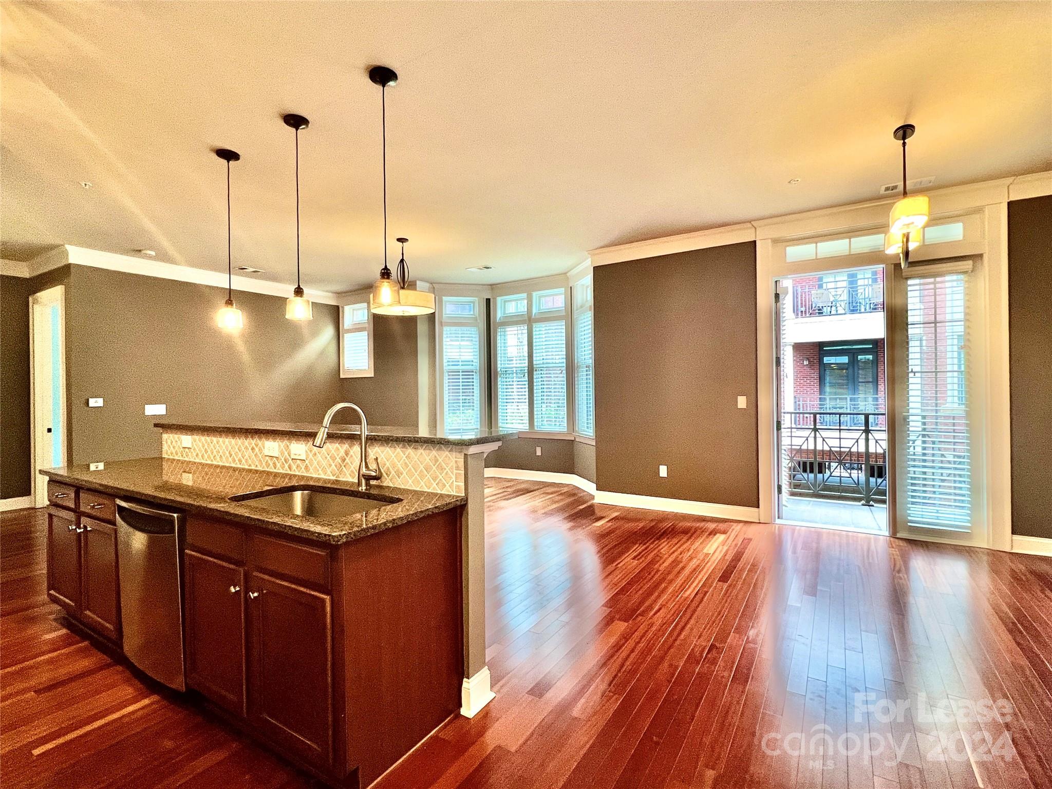 a kitchen with stainless steel appliances granite countertop a sink a stove and a wooden floors