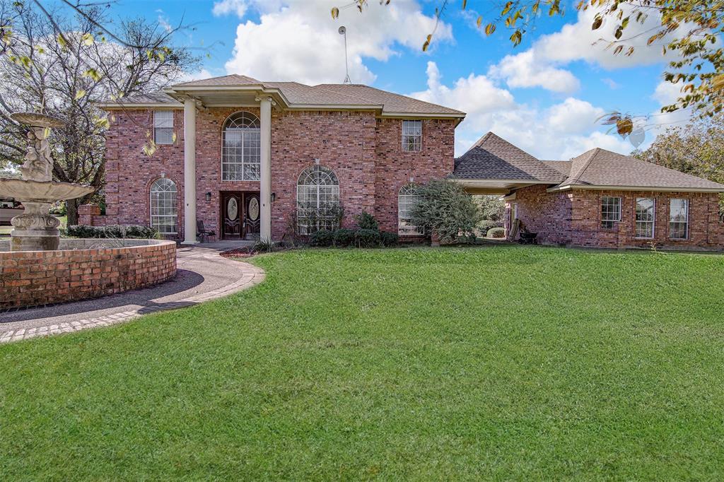 a view of a brick house with a big yard and large trees