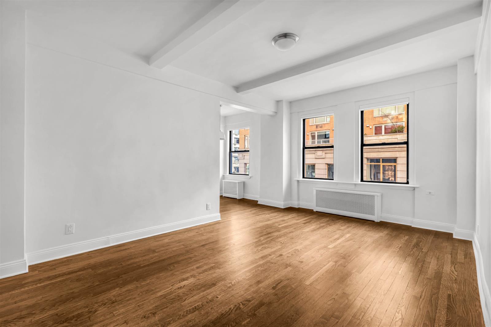 a view of an empty room with window and wooden floor