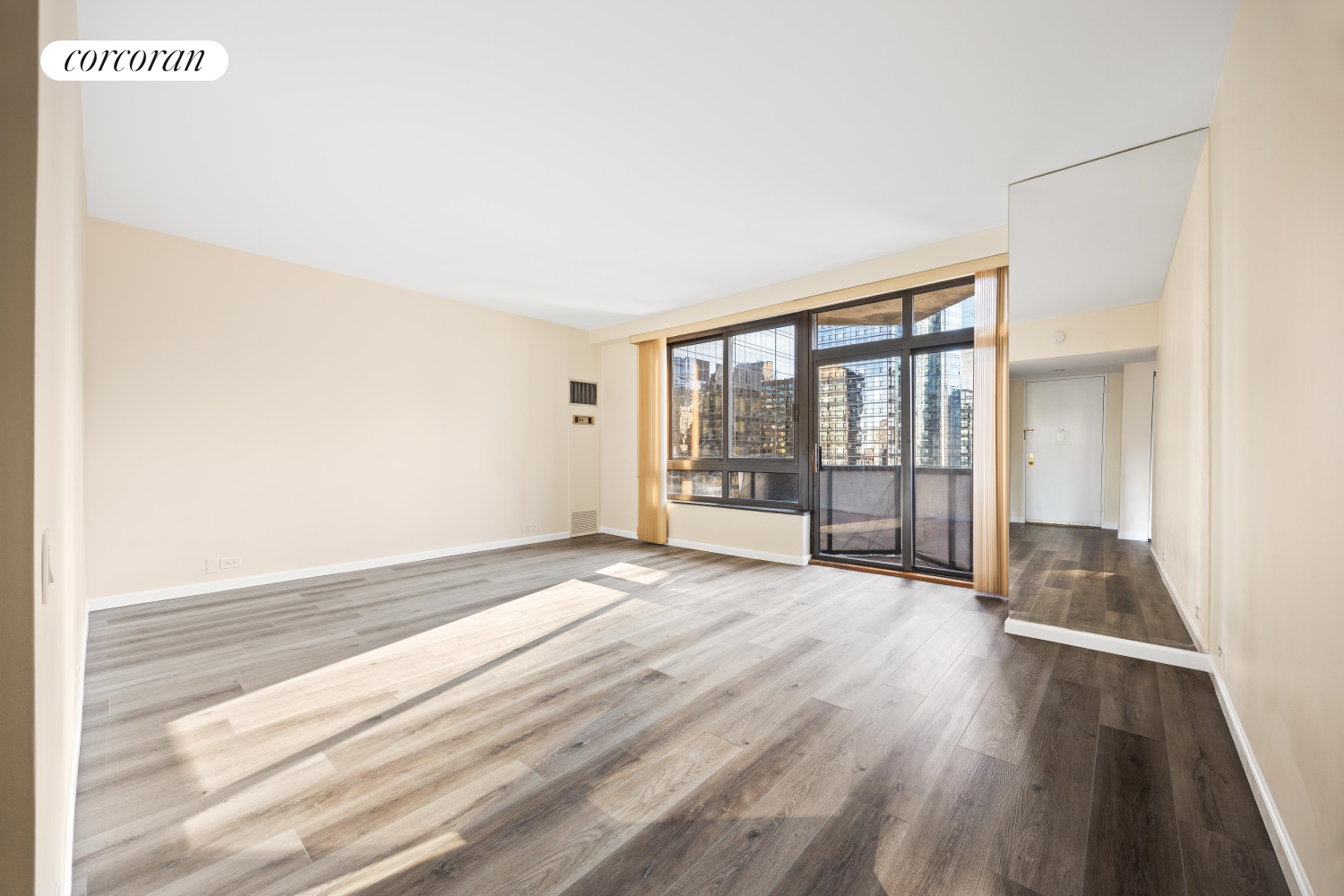 a view of an empty room with wooden floor and a window