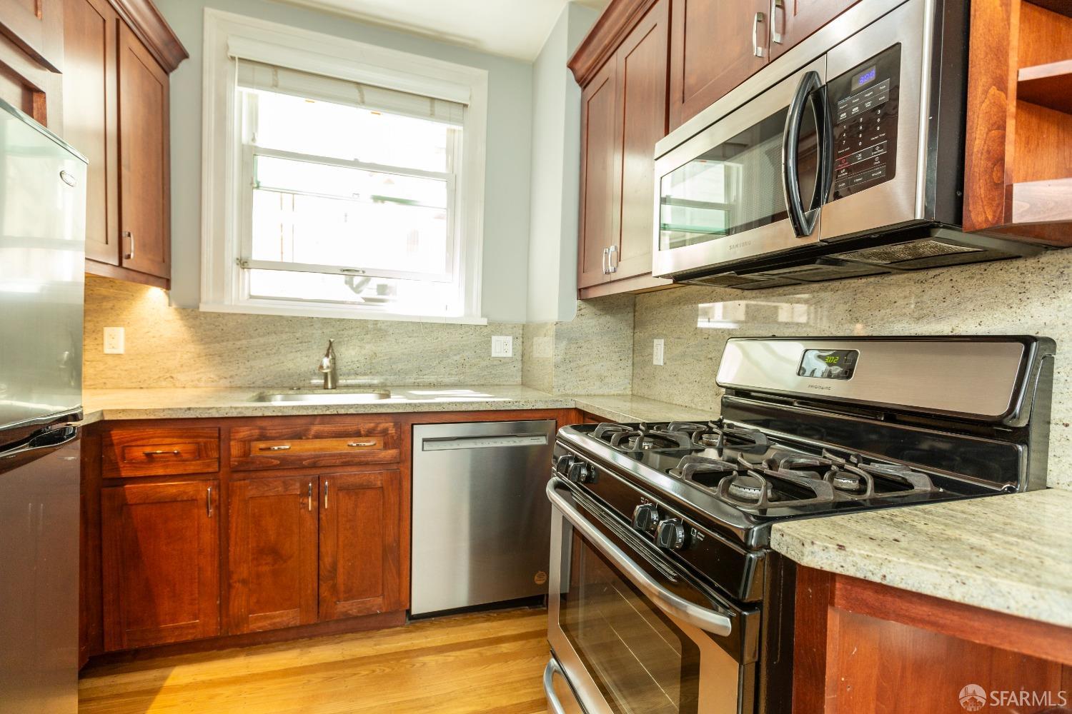 a kitchen with stainless steel appliances granite countertop a stove a sink and a microwave