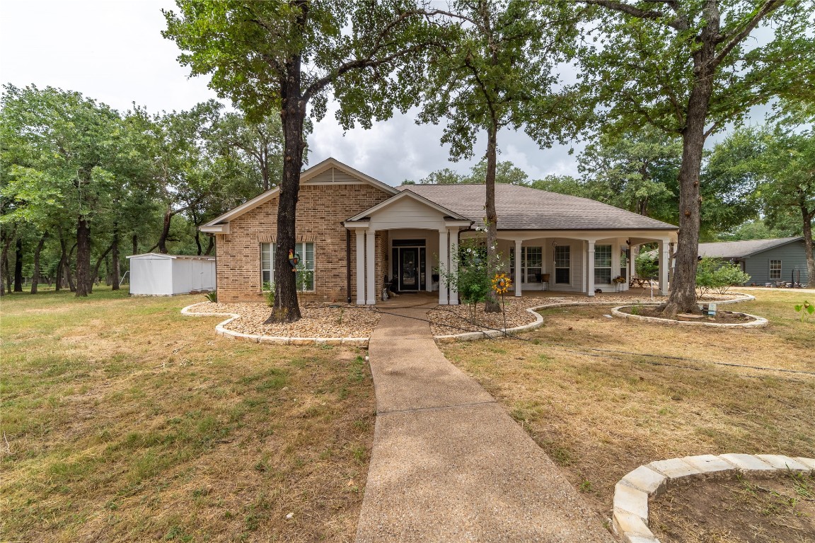 a front view of a house with a garden and tree