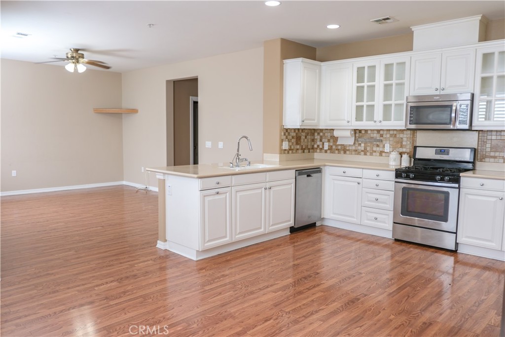 a kitchen with stainless steel appliances granite countertop a stove top oven a sink and white cabinets