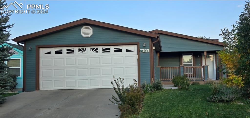 Ranch-style home featuring a front lawn, covered porch, and a garage