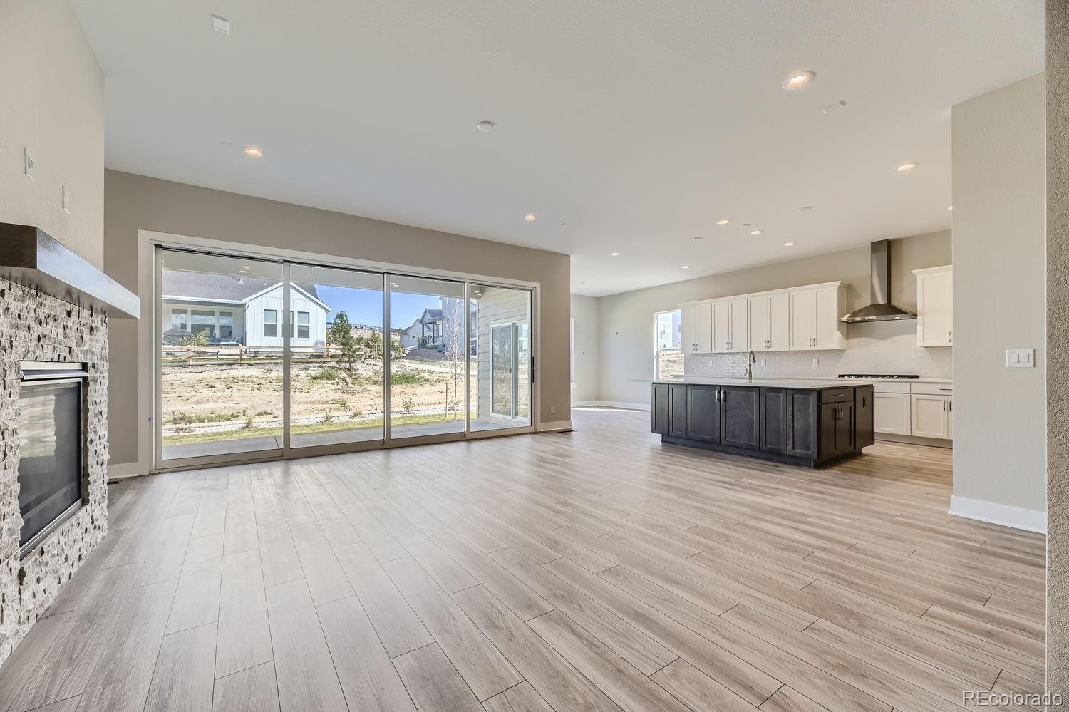 a view of an empty room with wooden floor and a fireplace