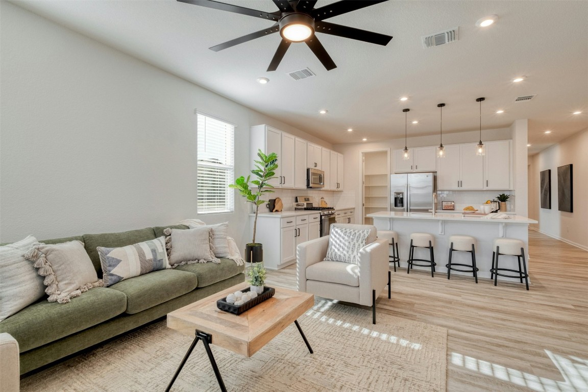 a living room with furniture kitchen view and a chandelier