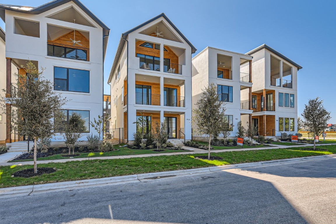 a front view of multi story residential apartment building with yard and green space