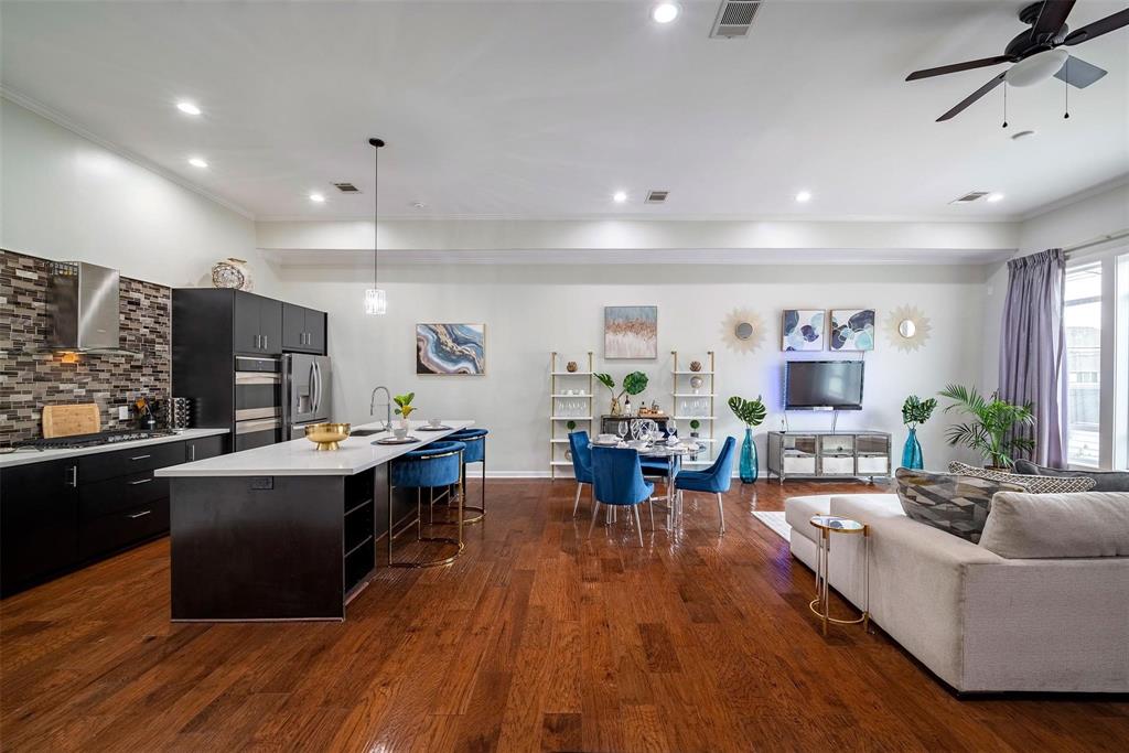 a living room with furniture kitchen view and a wooden floor