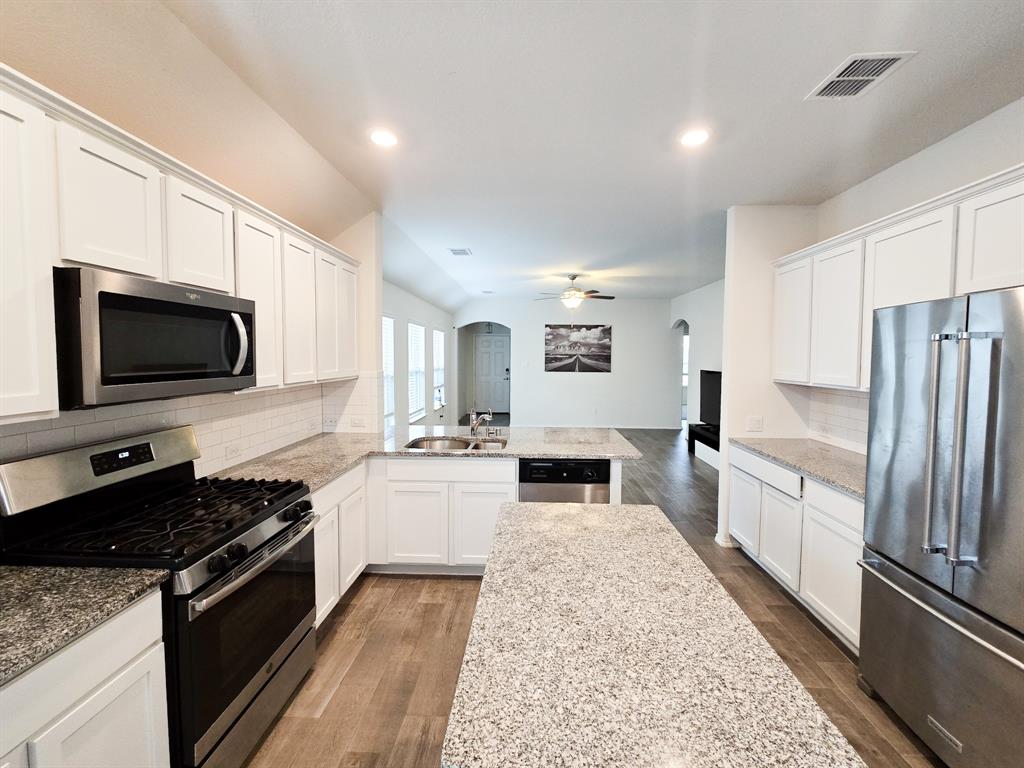 a large kitchen with stainless steel appliances granite countertop a stove a sink and a microwave