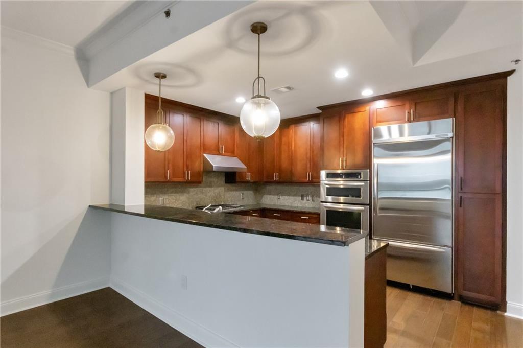 a kitchen with granite countertop a refrigerator a oven and a sink