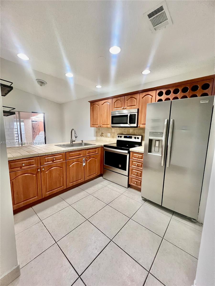 a kitchen with stainless steel appliances granite countertop a stove top oven a sink dishwasher and a refrigerator