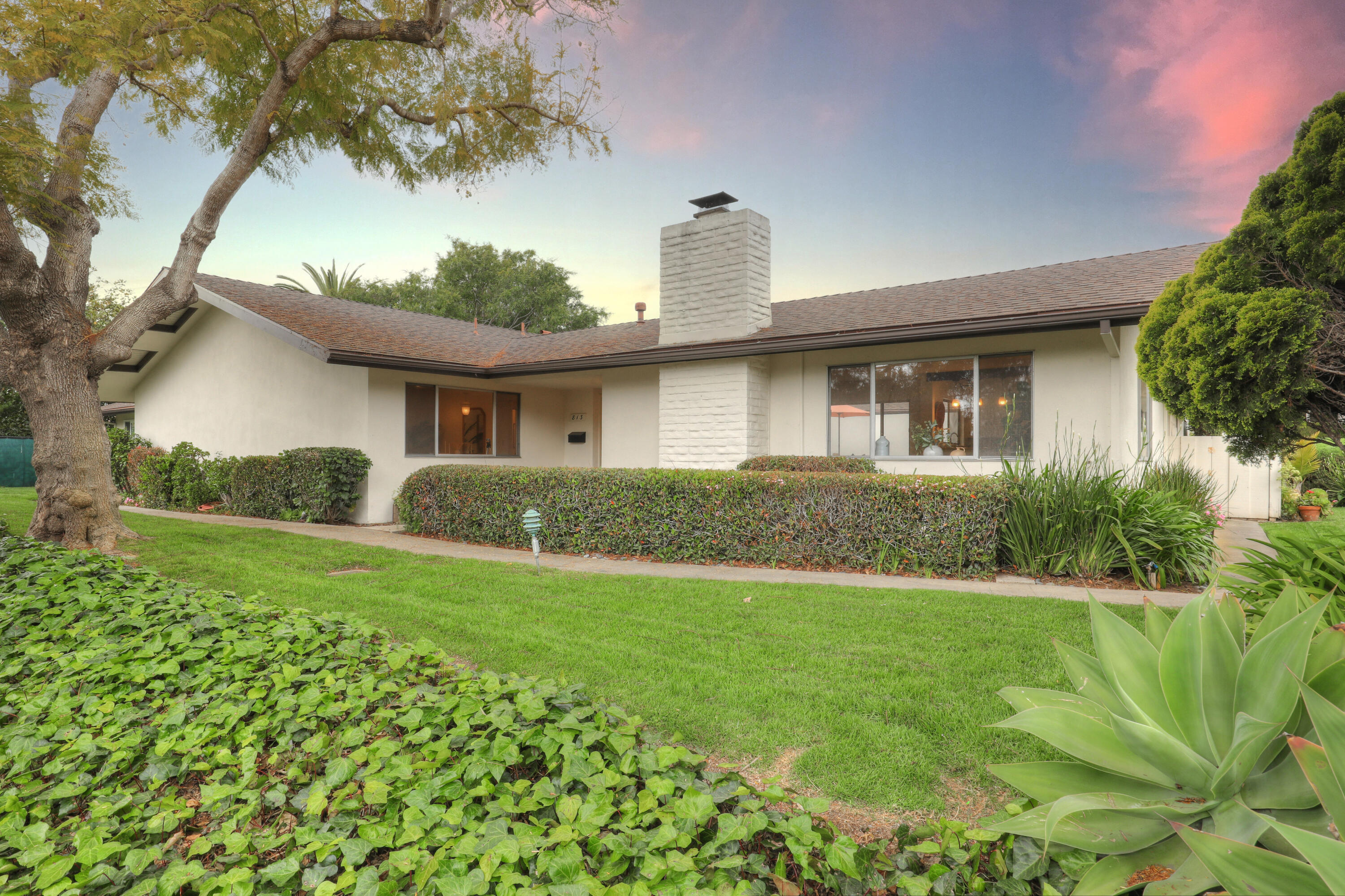 a view of a house with a big yard plants and large trees