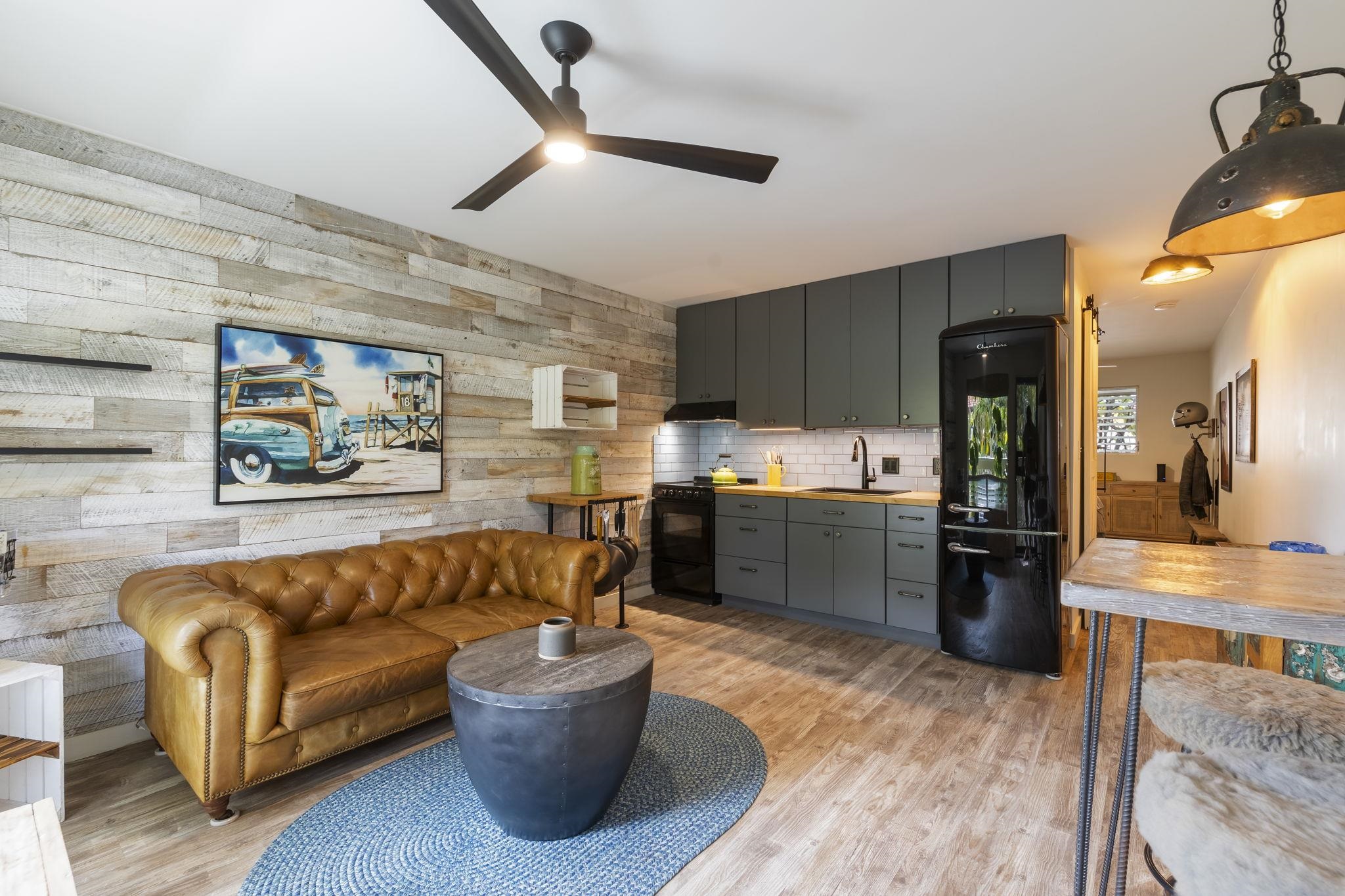 a living room with stainless steel appliances furniture and a kitchen view