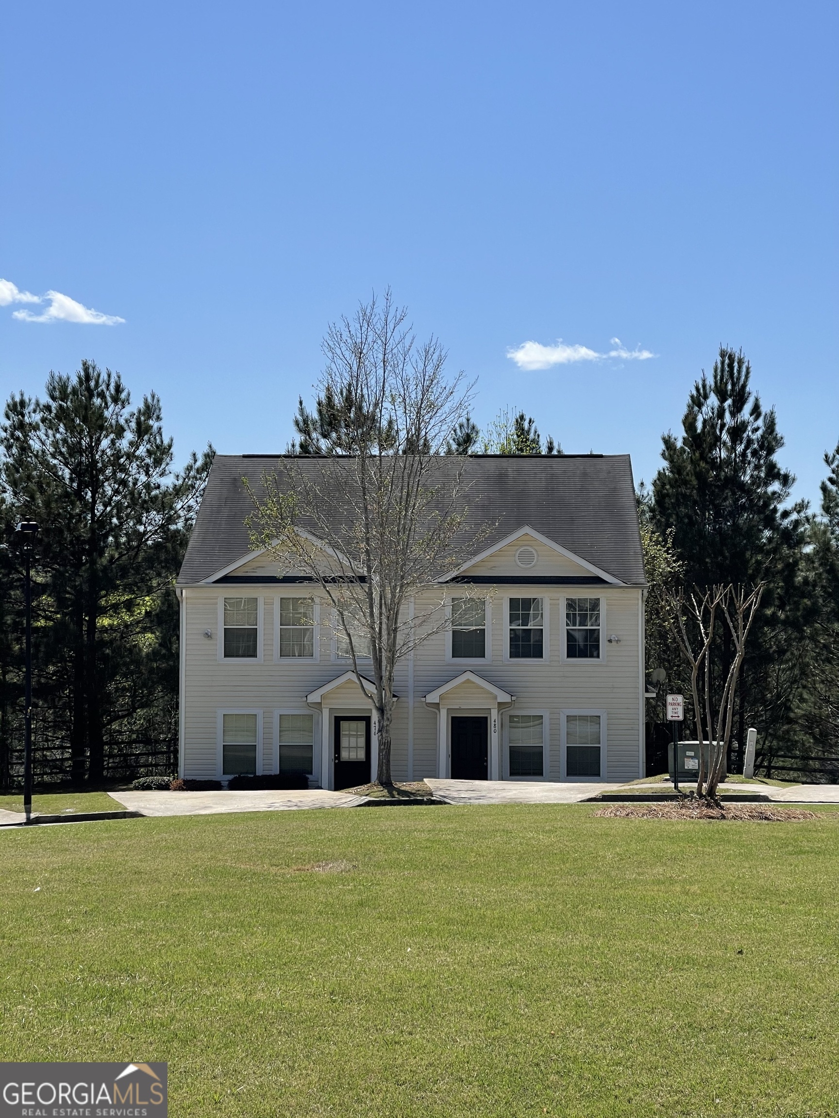 a front view of house with yard and trees in the background