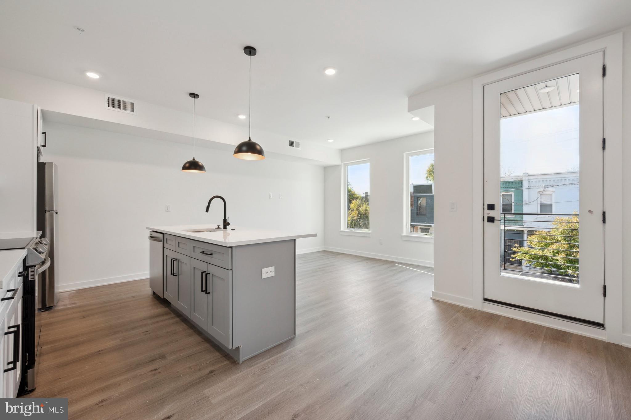 a kitchen with stainless steel appliances granite countertop a sink a stove and a wooden floors