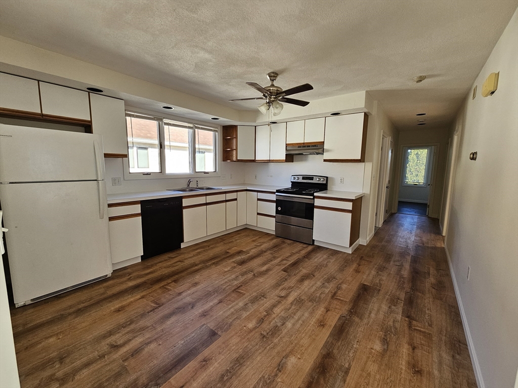 a kitchen with granite countertop a refrigerator stove top oven and sink