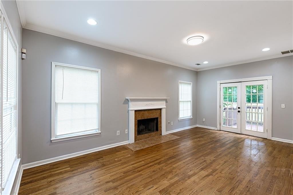 an empty room with wooden floor fireplace and windows