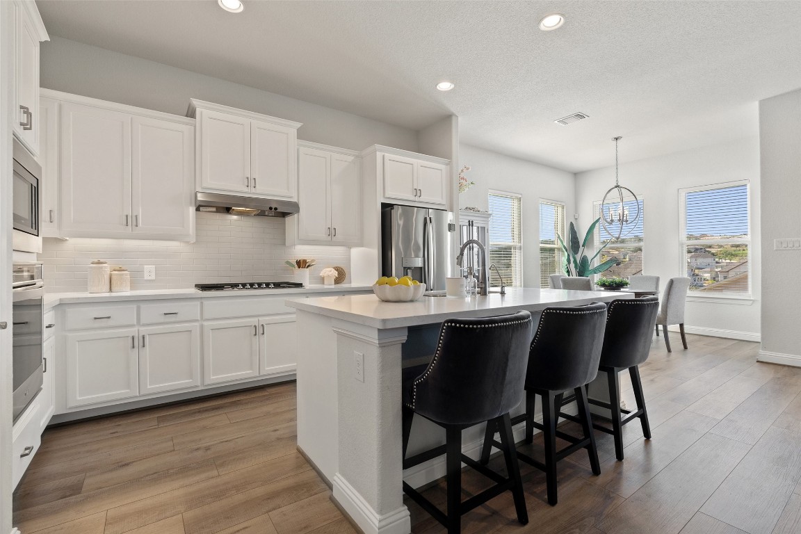 a kitchen with stainless steel appliances granite countertop a white cabinets and wooden floors