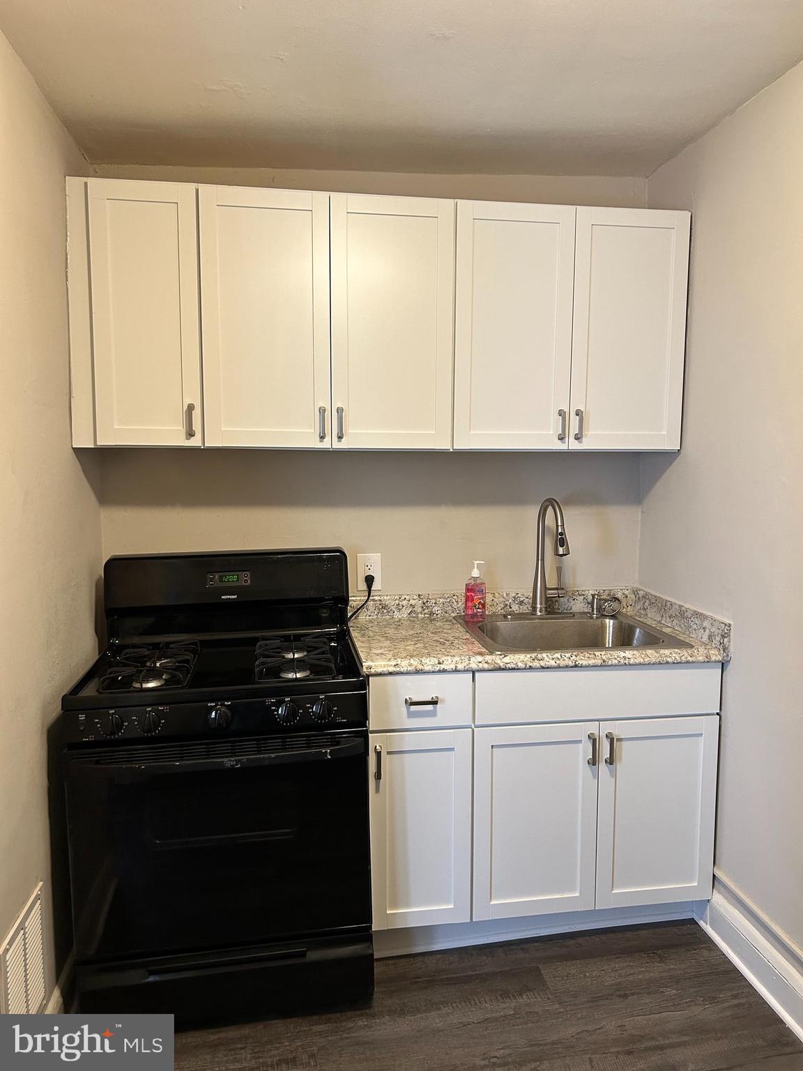 a kitchen with granite countertop white cabinets and stainless steel appliances