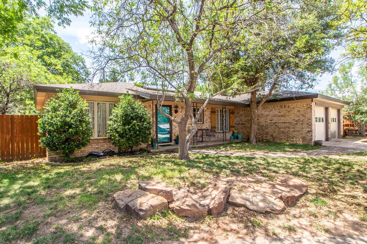 a backyard of a house with plants and large tree