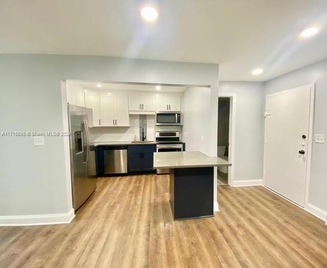 a large kitchen with stainless steel appliances kitchen island a large counter top and wooden cabinets