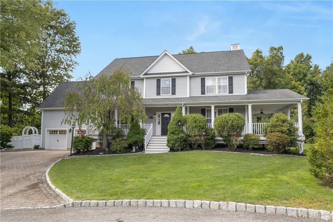 View of front of home featuring a garage, a front yard, and covered porch