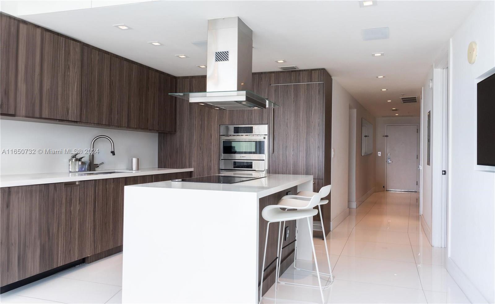 a kitchen with stainless steel appliances kitchen island granite countertop a refrigerator and a sink