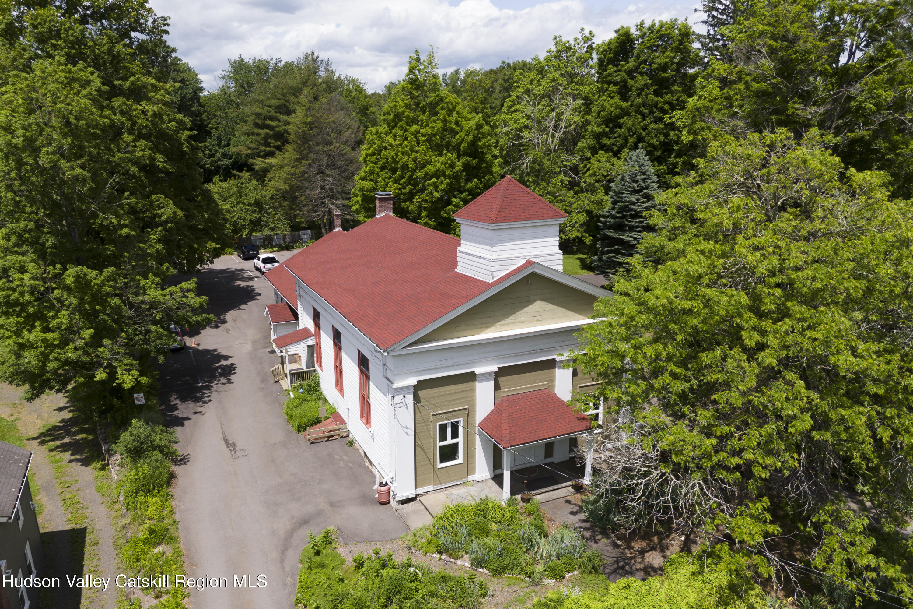 an aerial view of a house with yard and trees in the background