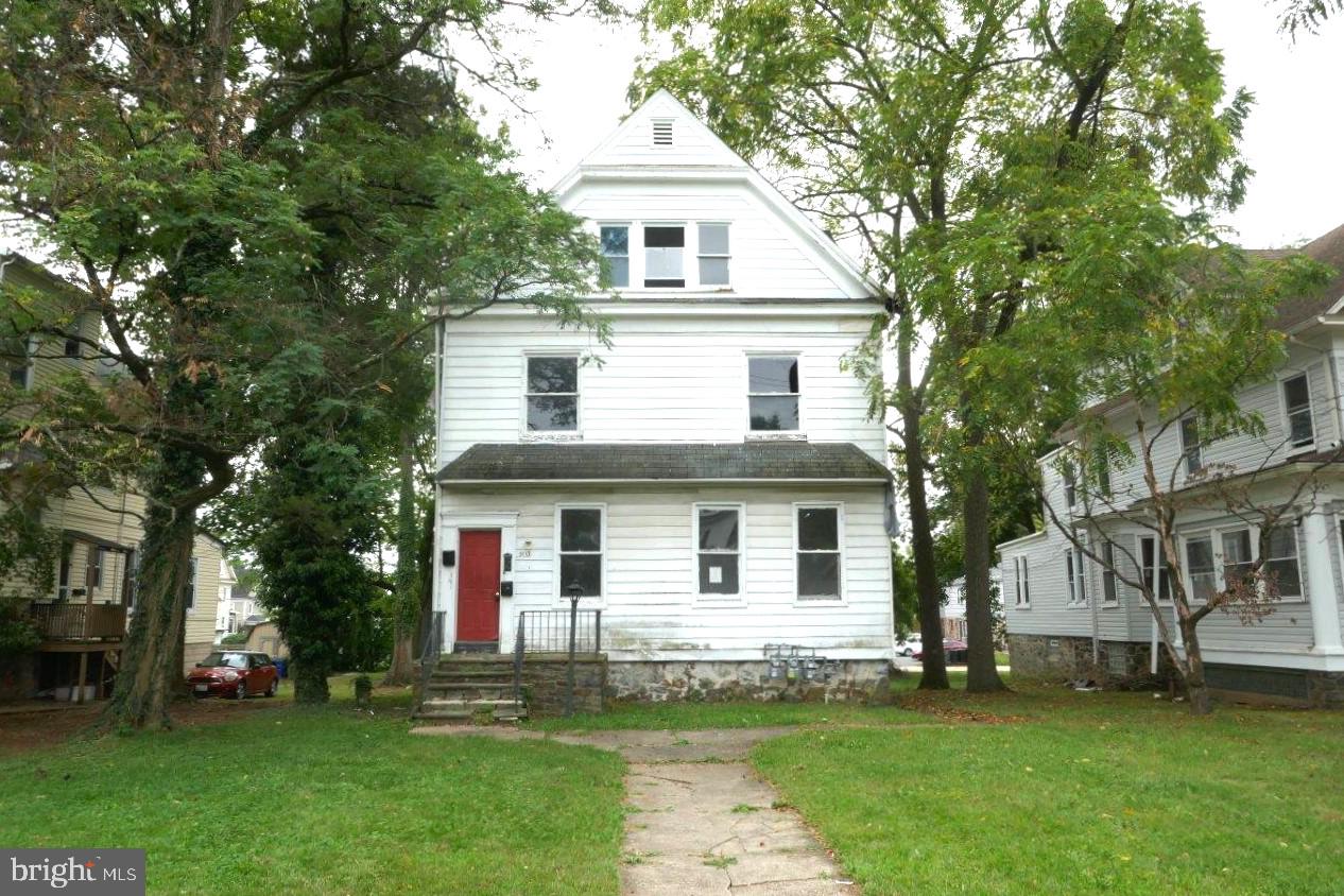 a white house with a large tree and yard