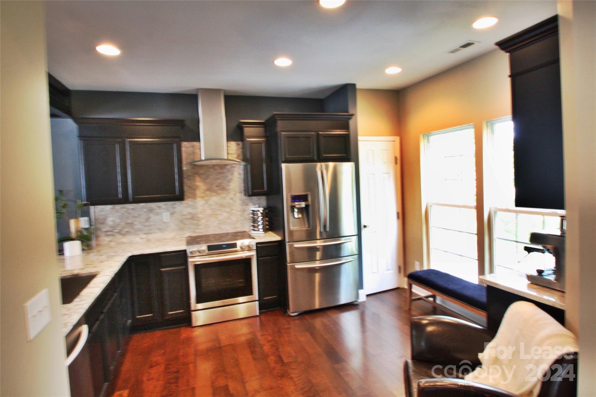 a kitchen with stainless steel appliances granite countertop a refrigerator and a stove top oven