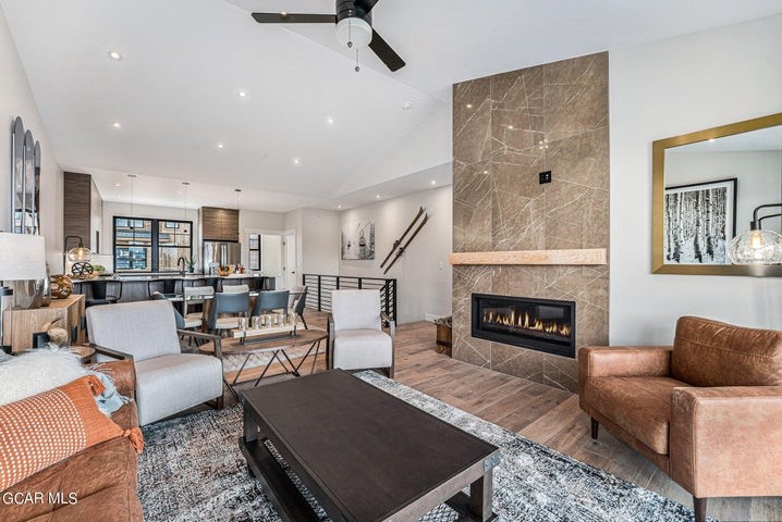 Living room featuring tile walls, a fireplace, wood-type flooring, and ceiling fan