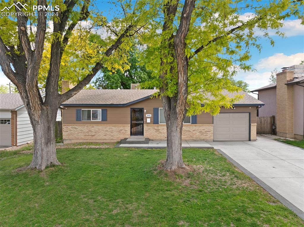 a front view of a house with a yard and tree