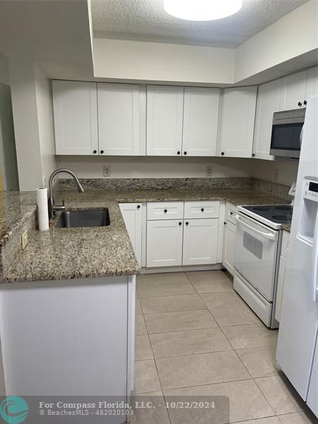 a kitchen with granite countertop white cabinets and stainless steel appliances