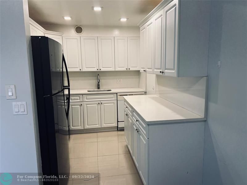 a kitchen with a sink a refrigerator and cabinets