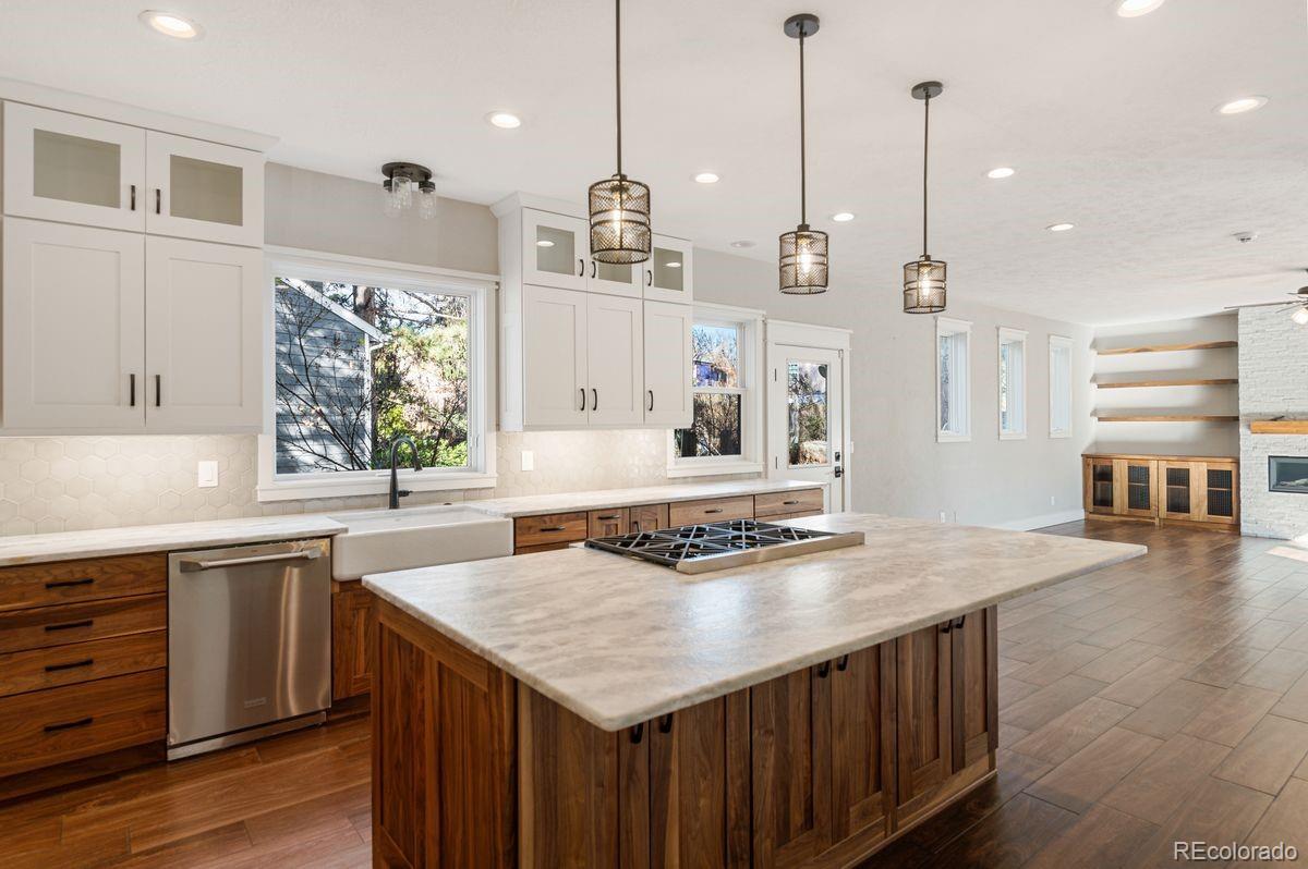 a kitchen with stainless steel appliances granite countertop a sink a stove and a wooden floor