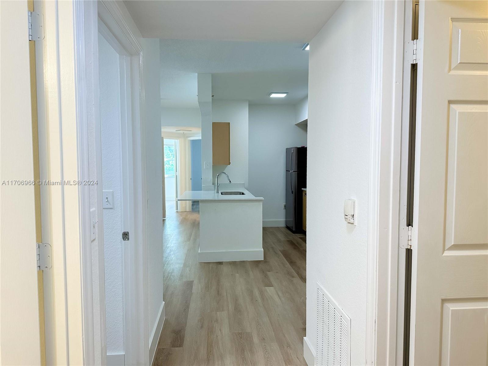 a view of a hallway with wooden floor and a bathroom