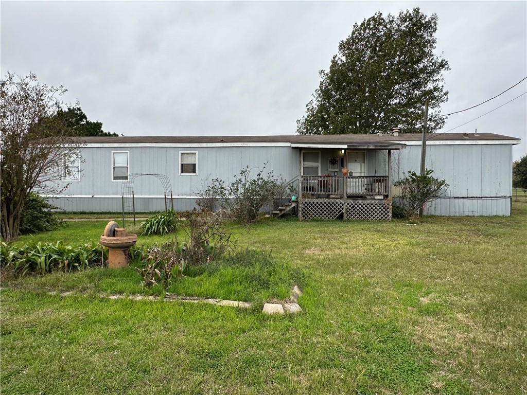 Back of house featuring a wooden deck and a lawn