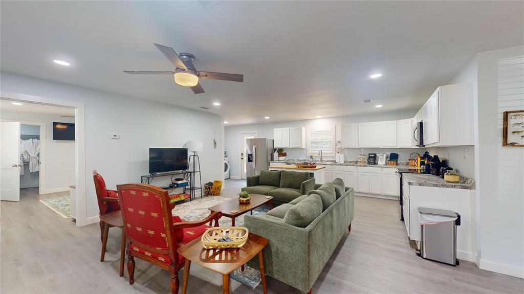 a living room with furniture kitchen view and a wooden floor